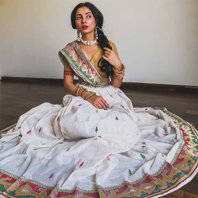 Elegant Garba saree-style lehenga look in white and gold with traditional jewelry for Navratri