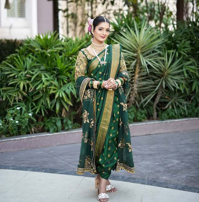 Marathi woman in green Nauvari saree with golden embroidery and traditional jewellery.