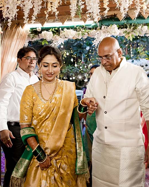 Woman in golden silk saree with green border at traditional Maharashtrian wedding