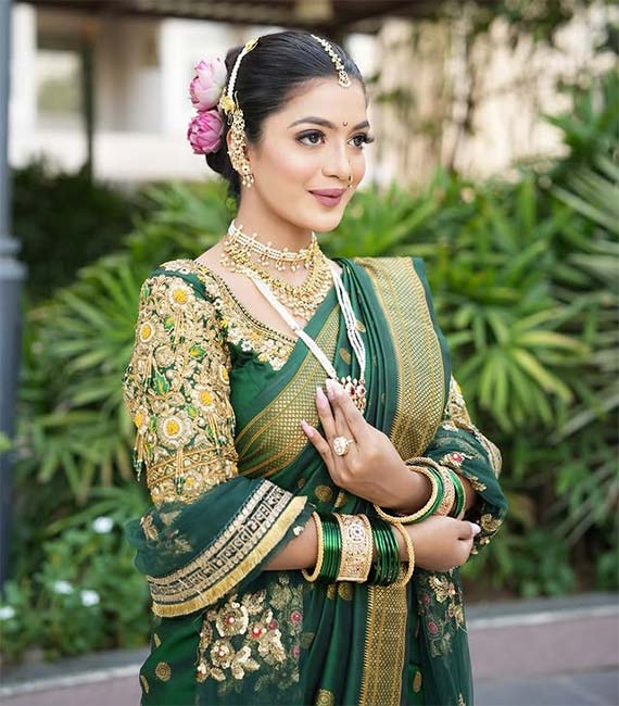 Marathi bride in green Nauvari saree with golden embroidery and traditional jewellery.