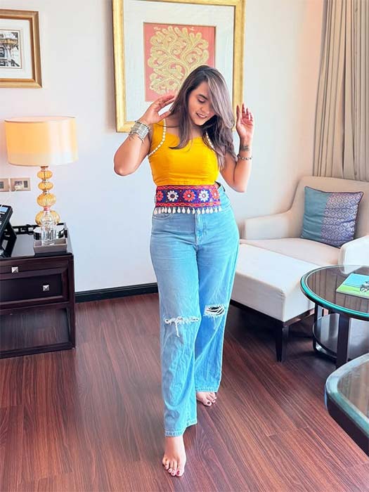 Girl wearing yellow blouse with jeans and embroidered belt for Navratri