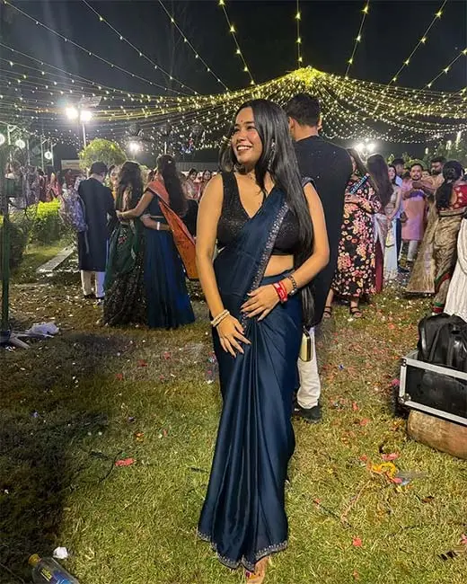 Beautiful young woman in a navy blue saree with black sequin blouse enjoying Garba night under festive lights