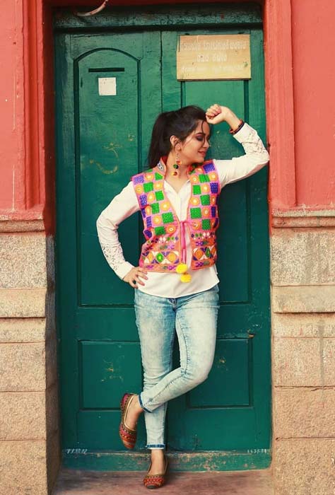 Girl in jeans and white shirt styled with colorful Gujarati embroidered jacket – Navratri look with jeans.