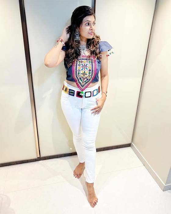 Girl in embroidered crop top with mirror work paired with white jeans and ethnic belt β Indo-Western Navratri look.