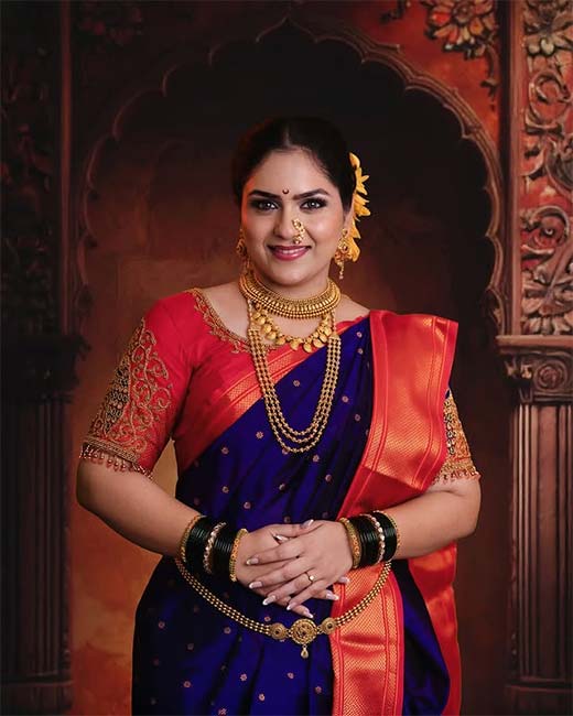 Woman in navy blue silk saree with red blouse and traditional Maharashtrian jewellery