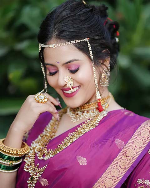 Maharashtrian bride in purple Nauvari saree with gold jewellery, nath, and maang tikka.