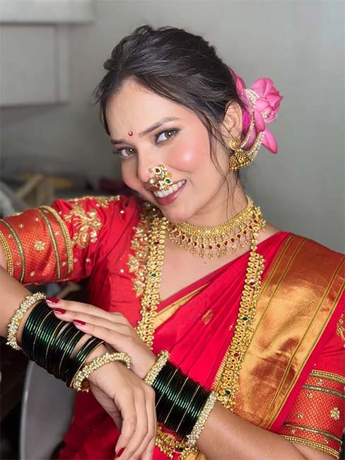 Woman in red silk saree with golden border and traditional Maharashtrian jewellery
