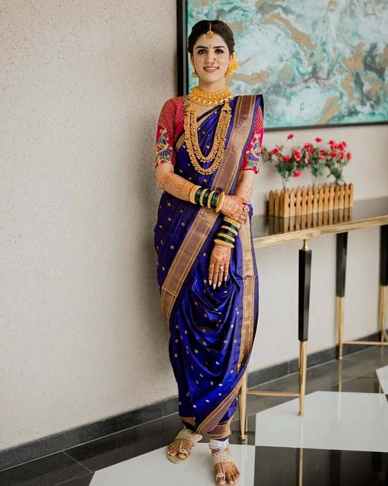 Woman in royal blue Nauvari saree with golden border and traditional Maharashtrian jewellery