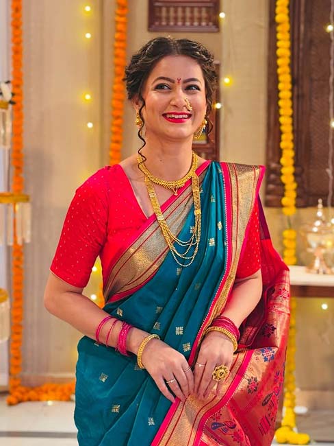 Woman in teal blue Paithani saree with pink blouse and golden jewellery