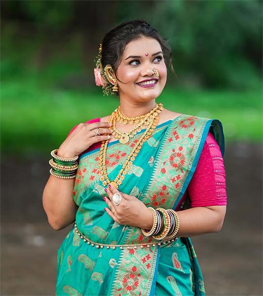 Bride in green Nauvari saree with gold jewellery and pink blouse